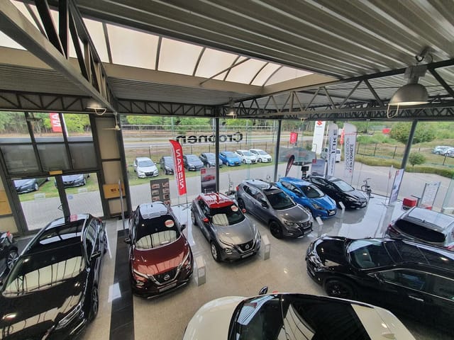 Interieur van een autodealer met verschillende Nissan-auto's in een showroom met grote ramen