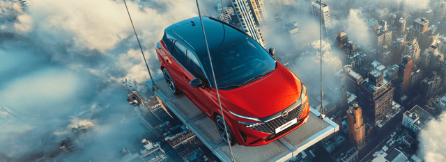 Rode Nissan Qashqai auto hangend op een platform hoog boven een stad bedekt met wolken