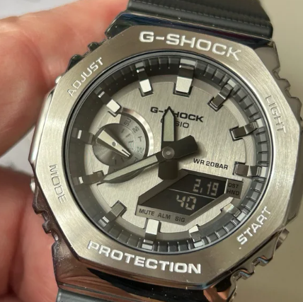 Primer plano de la esfera del supuesto Casio G-Shock GM-2110D-7A para revisar índices logotipos agujas y pantalla digital