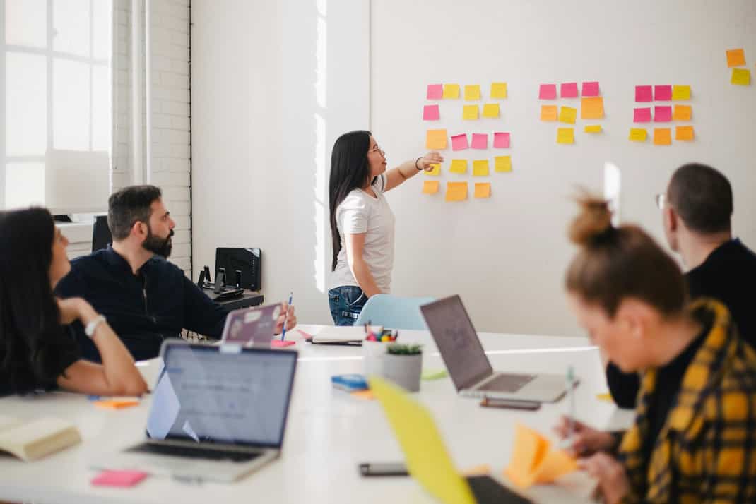 Một nhóm đang làm việc trong buổi workshop, một người dán giấy ghi chú lên tường