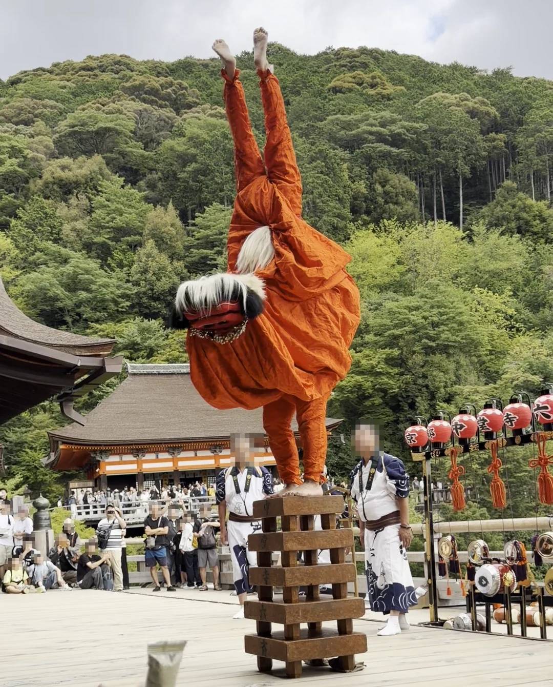 A lion dancer doing a handstand on a wooden tower during Rokusai Nenbutsu at Kiyomizu-dera