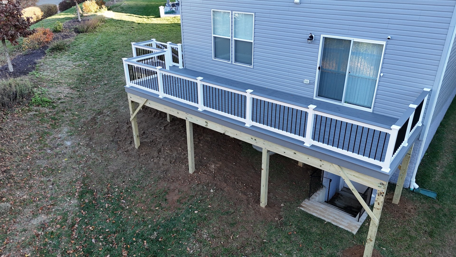 Elevated walk-out deck with Trex Select Pebble Gray decking and white vinyl railings in Cetronia, PA.