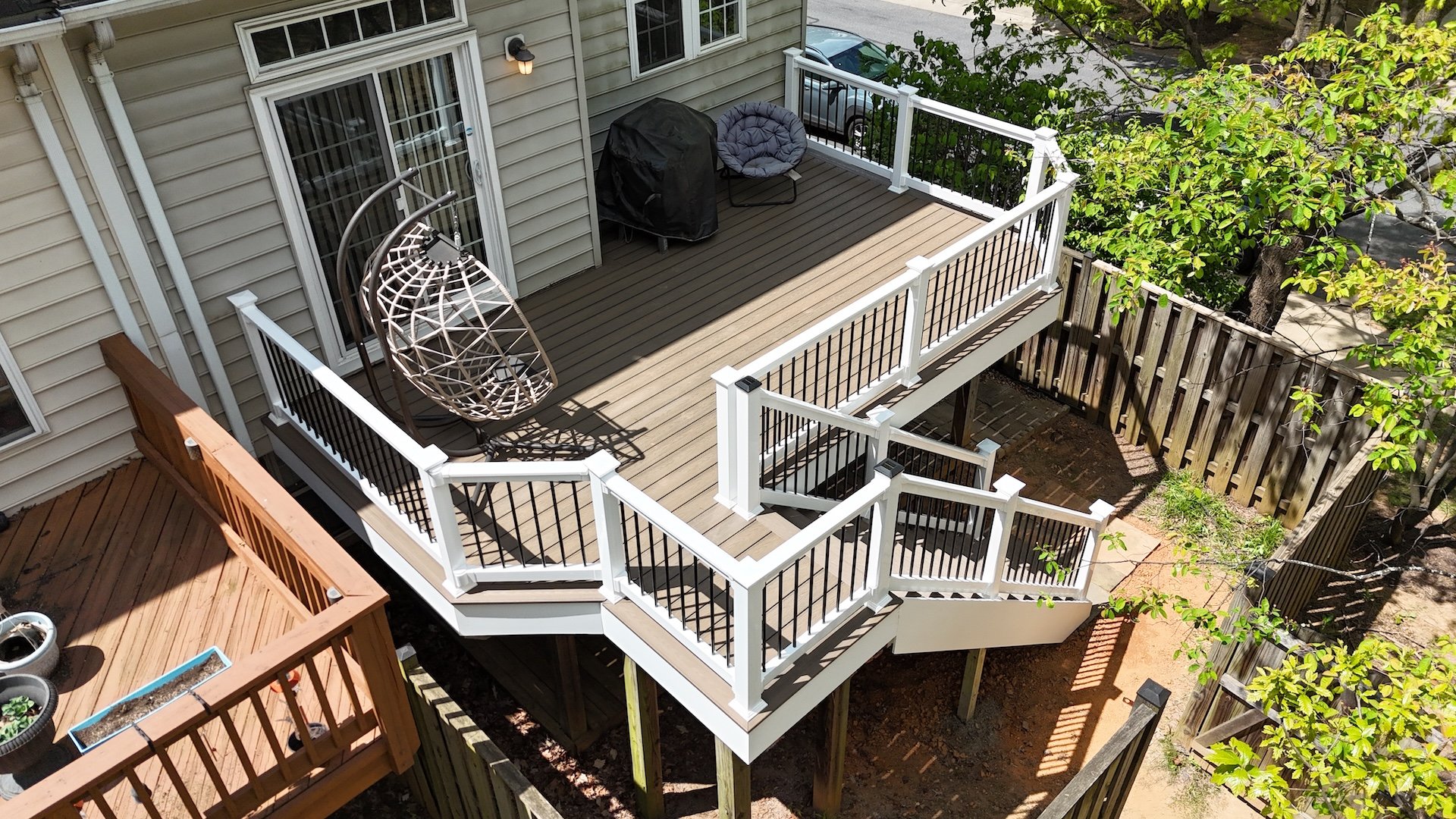 Deck renovation featuring Trex Enhance decking, white PVC fascia, and black aluminum balusters by Upgryd.
