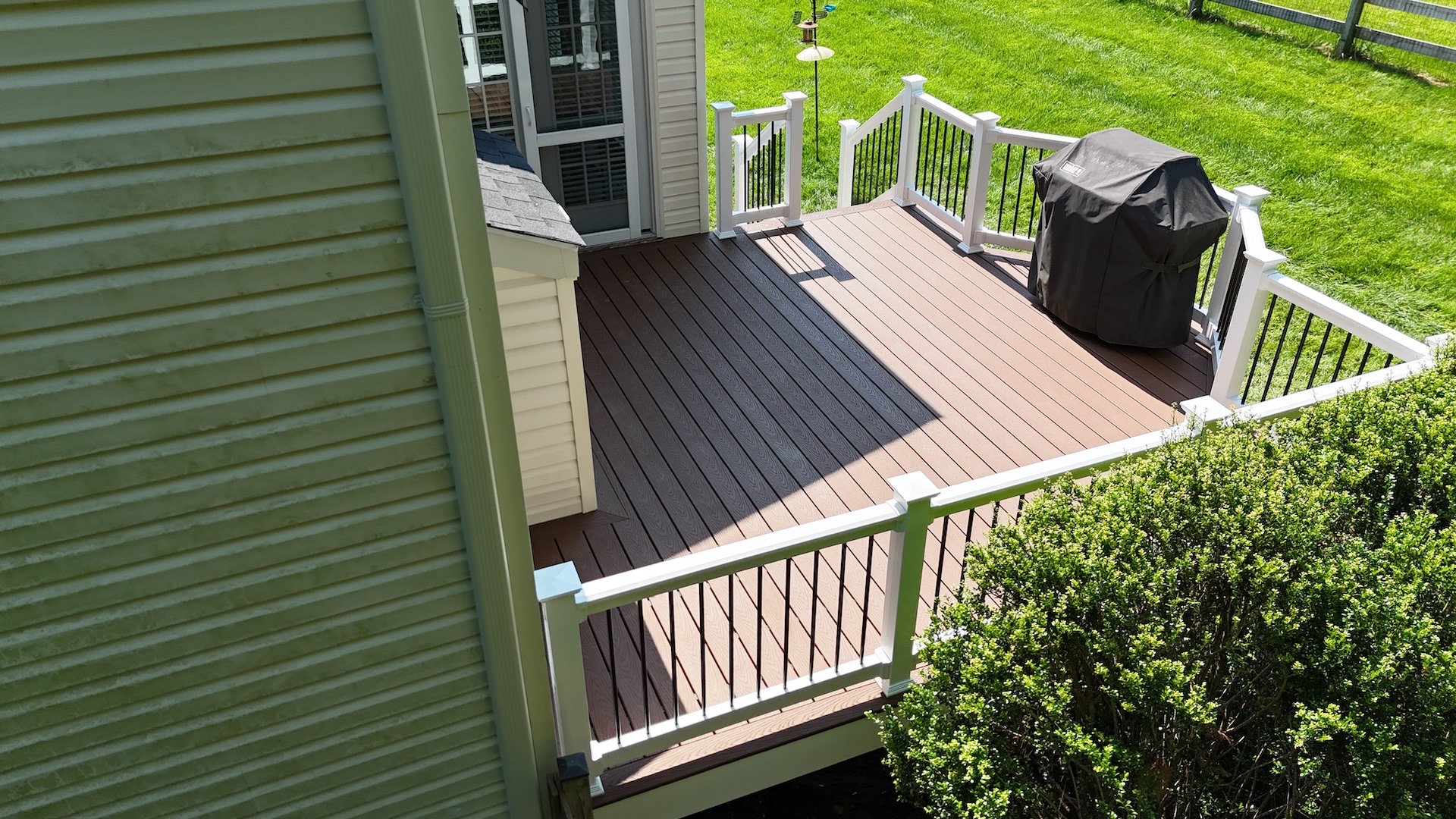 A modern deck transformation featuring Trex Select Decking in Saddle, complemented by durable vinyl railings and aluminum balusters.