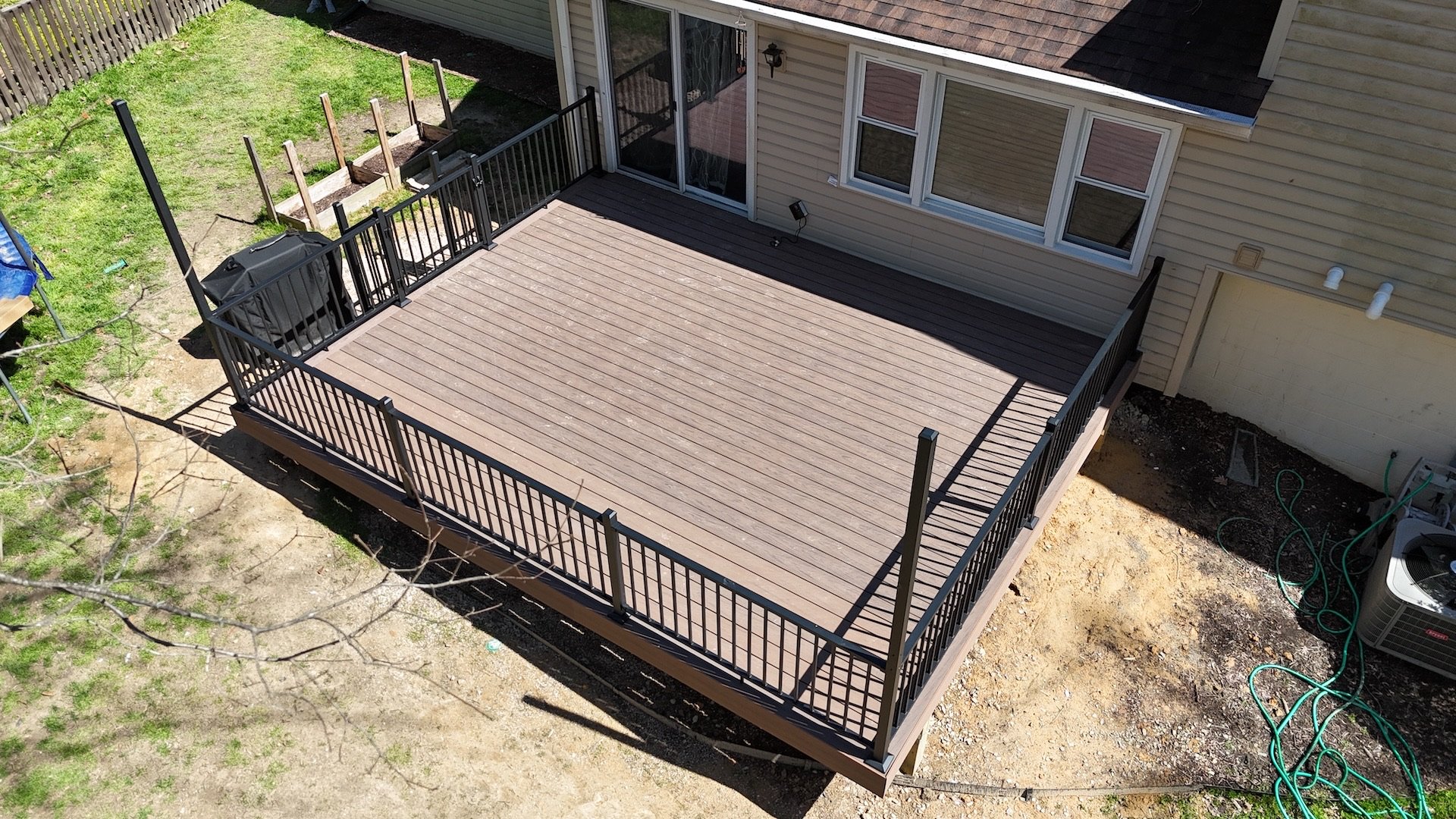 A top-down view of a newly built composite deck in Emmaus, PA, with Deckorators Vault Mesquite decking and black aluminum railings.
