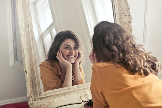 une femme souriante se regardant dans un miroir