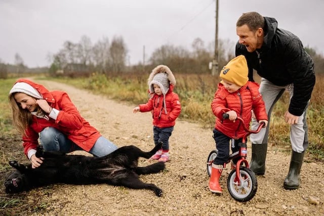 famille avec leur chien s'amusant lors d'une promenade