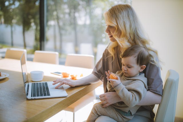 une femme devant son ordinateur avec son enfant sur les genoux