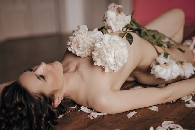 une femme allongée recouverte de fleurs blanche