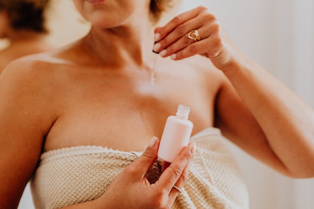une femme dans une serviette s'appliquant une huile corporelle