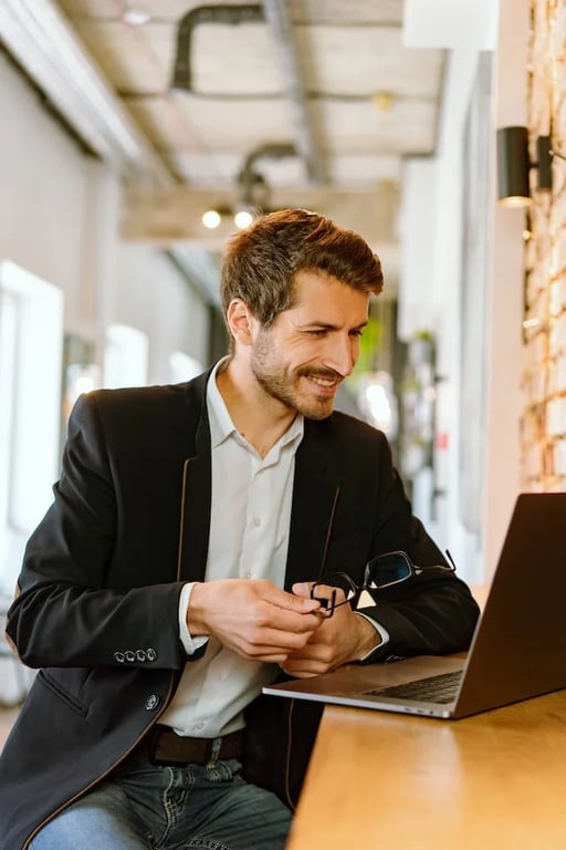 un homme habillé en costard souriant devant son ordinateur