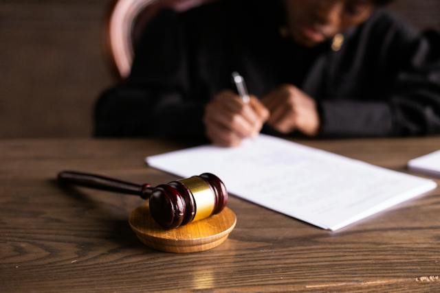 un juge rédigeant sur une feuille avec un marteau à côté