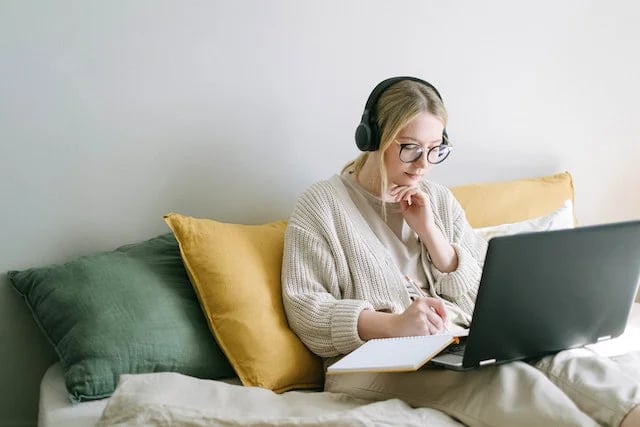 une femme sur son ordinateur avec un casque sur les oreilles 