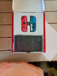 Herná konzola Nintendo Switch s neónovo modrým a neónovo červeným ovládačom Joy-Con, hybridná prenosná herná konzola, ktorú možno používať v režime TV aj v prenosnom režime. 2