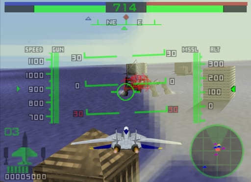 A fighter jet viewed from behind flies above a brown stepped pyramid structure on a desert landscape. The HUD displays green targeting brackets, speed readings on the left (1000, 900, 800 scale), altitude and missile counts on the right, and a circular radar in the bottom-right corner. A crosshair with diamond markers appears center-screen, with an enemy aircraft highlighted in the upper-middle distance. The top of the screen shows health/shield bars in blue, green, and red. The sky transitions from blue at the horizon to lighter tones, with a building visible on the right edge.