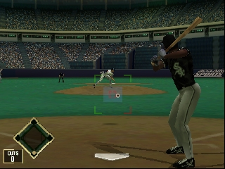 A batter in dark uniform stands ready at home plate with bat raised, facing a pitcher on the mound in a crowded stadium. The field features green grass with brown infield dirt, and a crowd fills the green-topped stadium seats in the background. A small diamond-shaped UI element appears in the lower-left corner, and the game view shows typical 3D polygon graphics with low-resolution textures characteristic of N64-era sports games. The pitcher and fielders are visible across the field under stadium lighting.