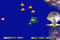 A green sea-monkey character swims in the center of a blue underwater environment. Several yellow jellyfish float in the upper portion of the screen, while a larger fish-like creature appears in the upper right. The bottom of the screen displays a UI bar with health/status icons on the left side and what appears to be game information or inventory slots on the right. The graphics use 8-bit sprite style with bright colors against a solid blue background.