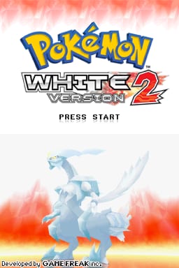 The title screen displays the Pokémon White Version 2 logo in blue and yellow at the top, with a red and white splattered background. Below the logo, the text "PRESS START" appears in white. A blue-tinted Pokémon creature, resembling a dragon-like figure with white accents, is positioned in the lower half against a gradient background transitioning from blue to red and orange flames. Developer credit "Developed by GAME FREAK inc." is visible at the bottom in small text.