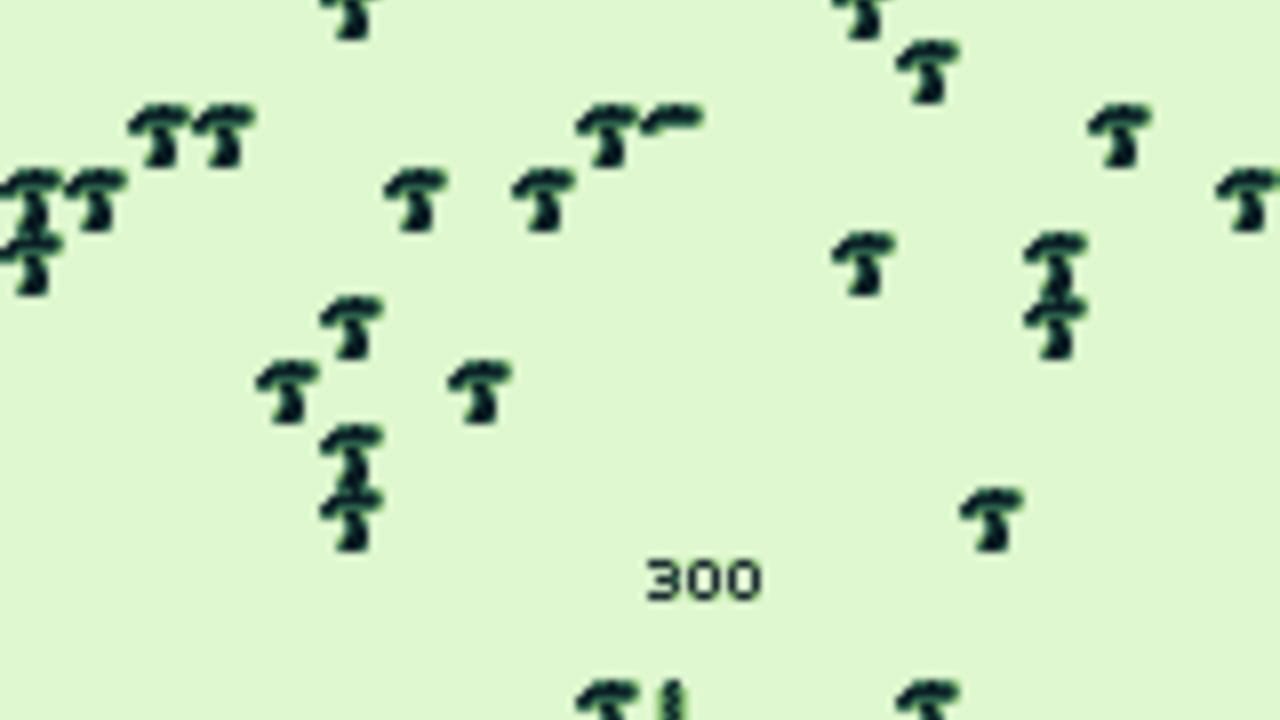 A light green screen filled with scattered dark blue mushroom sprites arranged across the playfield. The number 300 appears centered in the lower portion of the screen. Multiple mushroom shapes are distributed throughout, with denser clusters on the left side and sparser placement toward the right, typical of the early stage layout in a Centipede-style arcade game on Game Boy hardware.