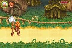 A small armored character stands on a yellow-green grassy platform in the center-left of the screen. The background features a brown wooden structure with green vines and decorative elements at the top, suggesting an underground or fantasy environment. The art style uses bright, flat colors with low-resolution sprites typical of GBA games. A UI panel appears in the upper corners showing what appear to be collectible icons or status indicators. Grass tufts and game assets are visible along the bottom edge of the screen.