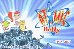The title screen features the Atomic Betty logo in large orange and blue letters at center-right, with a blue starburst background. To the left, a red-haired girl in yellow and white outfit stands next to a small yellow robot character. Below them is a rocky, debris-filled landscape in gray and dark tones. A "Press Start" button appears in the lower-right corner. The overall art style uses bright colors and simple sprite-based graphics typical of GBA games.