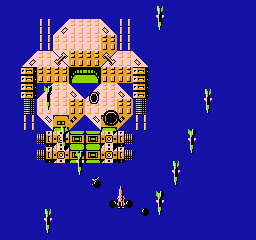 A large yellow and brown spaceship occupies the center of the screen against a solid dark blue background. The ship features geometric patterns, circular windows, and protruding engine sections. Multiple small white projectiles are scattered across the screen at various distances, appearing to descend toward the ship. A small yellow spacecraft with a pointed nose is visible near the bottom center. The sprite-based graphics use a limited NES color palette with clear pixelation typical of mid-1980s arcade ports.