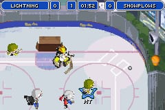 A top-down hockey rink view displays multiple player sprites positioned across the ice arena. The blue UI bar at top shows team names, score counters, and period information. Green-and-yellow and dark-colored player figures occupy various positions on the white rink with center markings. A brown puck sits near center ice. The right side shows a vertical scoreboard with team logos. Low-resolution pixel art characterizes the GBA-era graphics with flat color fills and simple sprite animation.
