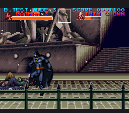 Batman in dark blue armor stands on a yellow and green checkered platform in the center-left of the screen. Above him, a large gray stone structure with pillars and stairs fills the background. The HUD displays Batman's health bar in red at top-left, an opponent's health bar at top-center, and a score counter at top-right showing 090100. A gray metal railing runs horizontally across the middle of the screen. The sprite-based graphics use a dark color palette with detailed pixel art typical of SNES-era action games.