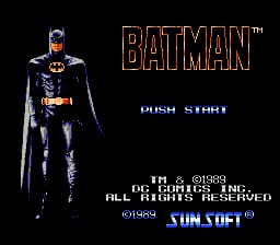 The title screen displays a full-body sprite of Batman in black armor with yellow accents, positioned on the left side against a black background. Large orange blocky text reading 'BATMAN' appears to the right of the character. Below are the words 'PUSH START' in white. Copyright text for JVC/DC Comics and Sunsoft appears at the bottom in small white type, along with the Sunsoft logo.