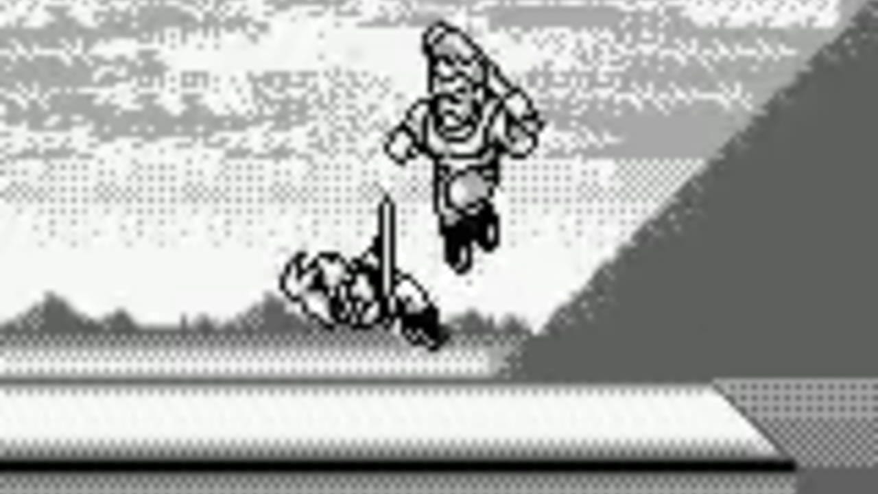 A monochrome Game Boy screenshot showing two pixelated fighters in mid-combat on a flat arena. The character in the foreground leaps upward with arms raised, while an opponent stands below wielding a staff or weapon. The background features a mountainous landscape with a light sky rendered in dot-pattern shading typical of Game Boy hardware. A white horizontal strip separates the playing field from the darker ground plane below.