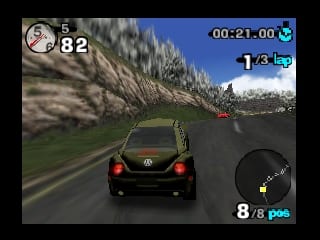 A green Volkswagen Beetle drives on an asphalt road through a mountainous landscape with dense forest and snow-capped peaks visible in the background. The first-person dashboard view shows the car's rear lights ahead on the track. A circular minimap appears in the bottom-right corner displaying track position and other racers. The top-left shows the player's race position as 82, with a lap counter reading 1/3 at top-right and a time display of 00:21.00. The HUD displays 8/8 gas at the bottom-right. The graphics use N64-era polygon modeling with visible texture detail on terrain and foliage rendered with parallax scrolling layers.