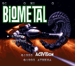 The BioMetal title screen displays the game's logo in large green capital letters at the top left. A mechanical blue and orange spacecraft or weapon platform occupies the right side of the screen, positioned over a rust-colored rocky terrain. A blue energy beam extends from the spacecraft toward the lower left. The Activision and Athena copyright notices appear at the bottom in white text. The background is solid black, with scanline effects typical of SNES-era graphics visible throughout.