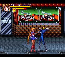 Two female fighters in colorful costumes face each other on a stone-tiled street during a fighting game match. The character on the left wears red and white, while the opponent on the right wears blue. Behind them are storefronts with Japanese signage and red-tiled roofing. The top of the screen displays two health bars with character portraits, a score counter showing "3", and remaining rounds indicator. The sprite-based graphics use a limited color palette typical of early 1990s SNES-era fighting games, with thick black outlines defining character forms.