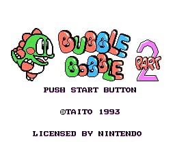 The title screen displays colorful, pixelated text reading 'BUBBLE BOBBLE' and 'PART 2' in large bubble-styled letters across the center. Below the title sits a small sprite character resembling a dinosaur or dragon on the left side, and a purple ghost sprite on the right. At the bottom, black text reads 'PUSH START BUTTON' followed by '@TAITO 1993' and 'LICENSED BY NINTENDO' in a standard 8-bit font. The background is solid black, and all graphics use the characteristic low-resolution sprite style of early NES games with bright red, green, blue, pink, and yellow colors.
