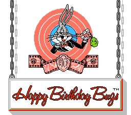Bugs Bunny's animated sprite occupies the center of the screen, depicted in a three-quarter view with characteristic long ears, white fur, and pink nose. He sits atop a large red and orange circular target pattern. Below this central image, a pink banner with red script lettering reads "Happy Birthday Bugs." The banner features decorative elements on either side resembling wrapped presents or gift boxes. Vertical chains hang from the top corners of the screen against a white background. The overall composition uses bright primary colors typical of NES-era graphics with moderate pixel resolution.