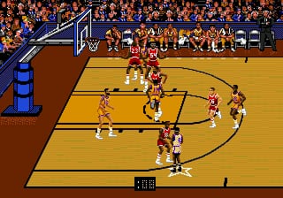 A basketball court is displayed from an overhead perspective with the Chicago Bulls in red uniforms positioned against the Lakers in yellow. Players are scattered across the wooden court floor with the ball in play near the center. A crowd of spectators fills the upper bleachers in blue and orange sections. The scoreboard shows "5-0" at the bottom center of the screen. A blue basketball hoop and backboard are visible in the upper left corner. The sprite-based graphics use a limited color palette typical of early 1990s Sega Genesis sports games.
