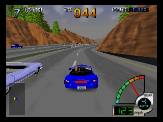 A blue sports car races down a wide highway flanked by brown rocky cliffs and green vegetation. Two other cars are visible ahead on the road. The HUD displays lap time 044 in the upper center, with position and time info in orange text. A speedometer dial and gear indicator occupy the lower-left corner. The road stretches into the distance under a gray sky, rendered in low-polygon 3D with visible texture mapping characteristic of N64-era graphics.