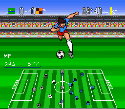 A soccer player in a blue and white uniform performs a kicking motion in the upper portion of the screen, with a soccer ball visible nearby. Below, an overhead tactical view displays a full soccer field with white line markings, player positions indicated by colored dots, and team formations visible on both sides of the center line. The UI shows match information including "MF" and "Subs" labels on the left, a score display at the top center, and a green grass pitch with stadium crowd visible in the background. The graphic style uses SNES-era sprite animation and 16-bit color palette.
