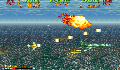 A top-down aerial combat view shows a yellow fighter jet in the lower-left firing at enemies over a densely packed cityscape. A large orange explosion erupts in the center-upper area, with smaller yellow projectiles and enemy fire visible. Multiple UI panels line the top of the screen displaying level, score, and other game information in red and yellow text. Three beige-colored ground targets are scattered across the city terrain. The sprite-based graphics use a blue sky background with green and brown pixelated urban structures below.