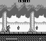 A monochrome Game Boy screenshot displays a pixelated protagonist in black silhouette standing on a stone platform in the lower-left area. Two tall stone pillars flank the scene against a cloudy sky backdrop with visible parallax scrolling. A score display reads "15131" at the top in a simple font. The lower portion shows a repeated brick tile pattern forming the ground level. The sprite resolution and color palette are characteristic of early Game Boy hardware limitations.