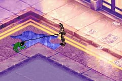 A character in dark clothing stands on a purple-tinted platform in an isometric perspective level. Blue water or liquid occupies a sunken rectangular area in the center of the screen, surrounded by yellow-outlined edges. The color palette is dominated by purples and magentas with pale yellow-green highlights. The graphics use low-resolution sprites typical of Game Boy Advance hardware, with pixelated environmental details and a overhead three-quarter view common to early 2000s portable action games.