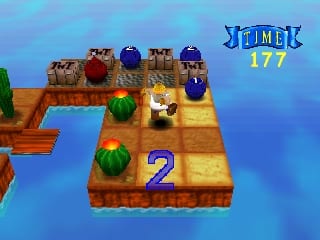 A 3D isometric platform level displays a wooden path with multiple colored spheres and geometric obstacles arranged across elevated sections. A large yellow number 2 marks the lower-right platform. Blue water surrounds the level at ground level. The sky shows a gradient from blue to cyan. A "JUMCK 177" score or level indicator appears in yellow text at the top-right corner. The architecture uses brown wooden textures with blue metallic sphere props placed strategically throughout the navigable space.