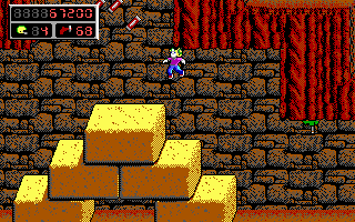 A blue pixel-art character stands on a platform made of stacked yellow and brown blocks against a brown brick wall with red striped pattern on the right. The top-left corner displays a score interface with numbers and small icons. The scene uses a limited 16-bit color palette with distinct pixelated sprites and tile-based level design typical of early 1990s DOS platformers.