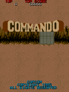 The arcade title screen displays large tan-colored block letters spelling 'COMMANDO' centered against a brown desert background with a green bunker structure beneath the text. Red score indicators and game text appear at the top of the screen, while blue copyright text reading 'COMMANDO COPYRIGHT 1985 ALL RIGHTS RESERVED' is positioned at the bottom. The overall color palette consists of earthy browns, greens, and reds typical of early 1980s arcade graphics.