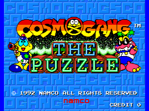 The title screen displays "COSMO GANG THE PUZZLE" in large green letters with a yellow outline centered on a blue checkered background. A red rounded character with large eyes floats to the left of the title, while two colorful alien creatures flank the right side. Below the logo, copyright text reads "© 1992 NAMCO ALL RIGHTS RESERVED" in red. A menu section labeled "DEMO" appears in the lower-right corner, with "CREDIT" visible to its right. The overall visual style uses bright primary colors typical of early 1990s arcade sprite graphics.