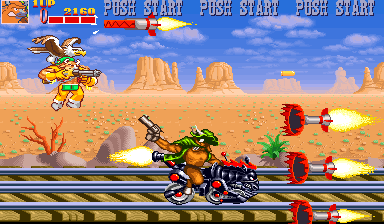 A brown anthropomorphic cow character rides a motorcycle across railroad tracks in the center-right of the frame, firing a gun at red mechanical enemies. Desert landscape with buttes fills the background under a blue sky. Explosions and projectiles burst across the middle of the screen. "PUSH START" text repeats in the top-right corner. The sprite-based graphics use a warm color palette of orange, tan, and brown tones with parallax scrolling vegetation.