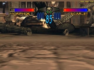 Two 3D-rendered fighting game characters clash in combat within an urban stone courtyard environment. The character on the left displays the name "MORPHIX" with a blue health bar, while the opponent on the right is labeled "SCARLET" with a red health bar. Both bars appear in the top corners of the screen. The ground shows concrete pavement with visible shadows cast by the fighters. The background features stone architecture and wooden structural elements typical of a stage arena. The graphics display the characteristic low-polygon style and muted color palette of early Nintendo 64-era 3D games.