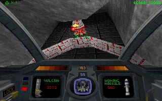 A first-person cockpit view displays a 3D tunnel with gray concrete walls converging ahead. At the center top, a red robot with yellow accents moves toward the player. The instrument panel below shows dark blue displays with green text readouts, including altitude and heading data on the left and right sides, with a central circular targeting reticle. HUD elements frame the viewport, and green text appears in the top-left corner. The environment uses low-polygon geometry typical of mid-1990s 3D graphics.