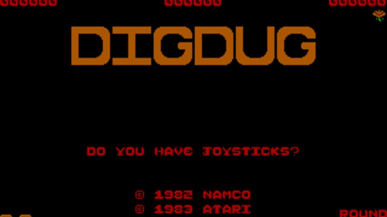 The title screen displays 'DIGDUG' in large orange pixelated lettering centered on a black background. Below it, red text asks 'DO YOU HAVE JOYSTICKS?' at mid-screen. Copyright information appears in red at the bottom, showing '© 1982 NAMCO' and '© 1983 ATARI'. A small decorative flower sprite appears in the top-right corner, and red circular shapes line the top edge. The entire interface uses a limited 8-bit color palette typical of early 1980s arcade ports.