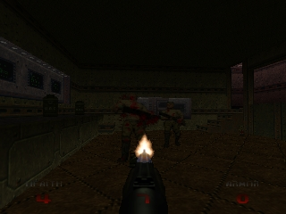 A first-person view down a dark industrial corridor lined with metal fencing and concrete structures. A weapon with a bright muzzle flash fires in the center foreground, illuminating the barrel and surrounding area. The HUD displays ammunition and health information in the lower corners. The scene uses a limited, dark color palette dominated by grays, blacks, and browns, characteristic of Doom 64's low-polygon 3D graphics and lighting effects.